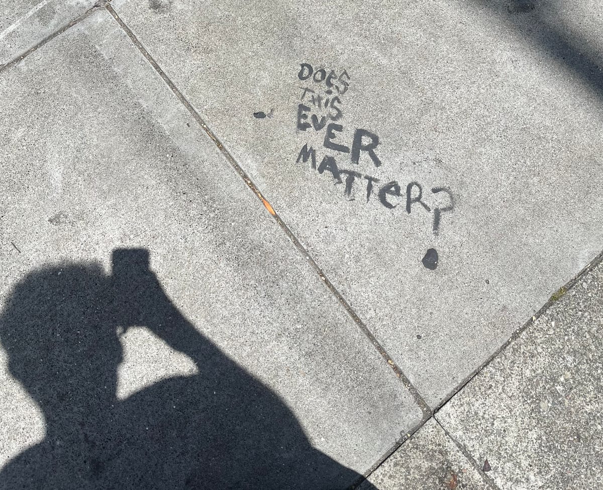 Writing on the sidewalk saying "Does this ever matter?"