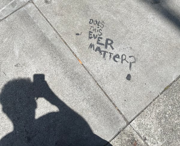 Writing on the sidewalk saying "Does this ever matter?"